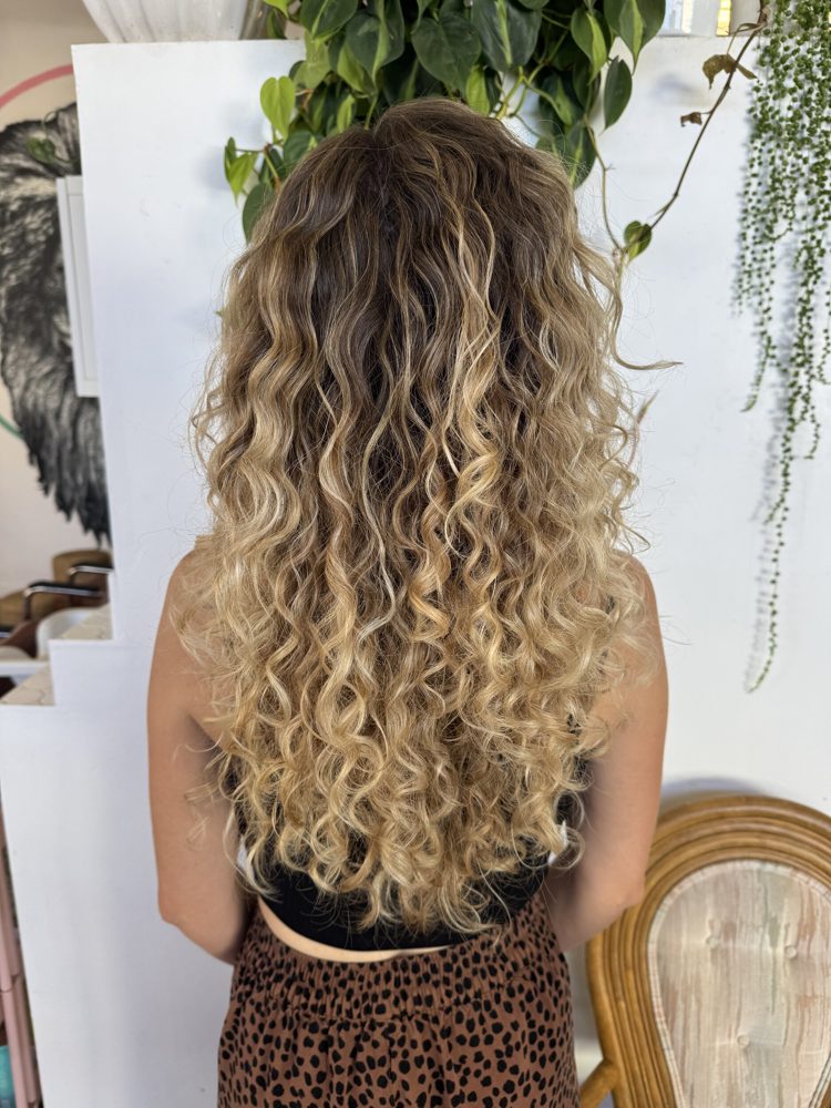 Sun-kissed dimensional color on long curly hair, San Diego